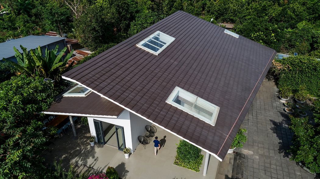 A modern house with a dark slanted roof, large windows, and a lush, green surroundings.