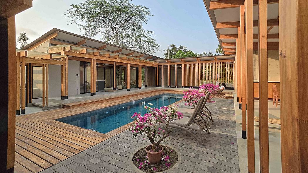 A modern, wood-framed structure with a swimming pool, patio, and lush vegetation.