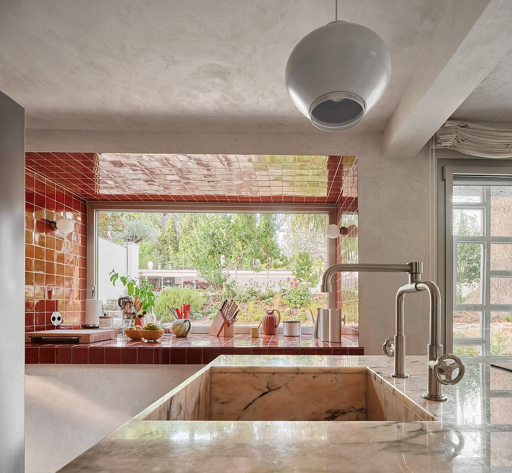 Sleek kitchen with brick accent wall, marble countertop, and large window showcasing lush greenery.