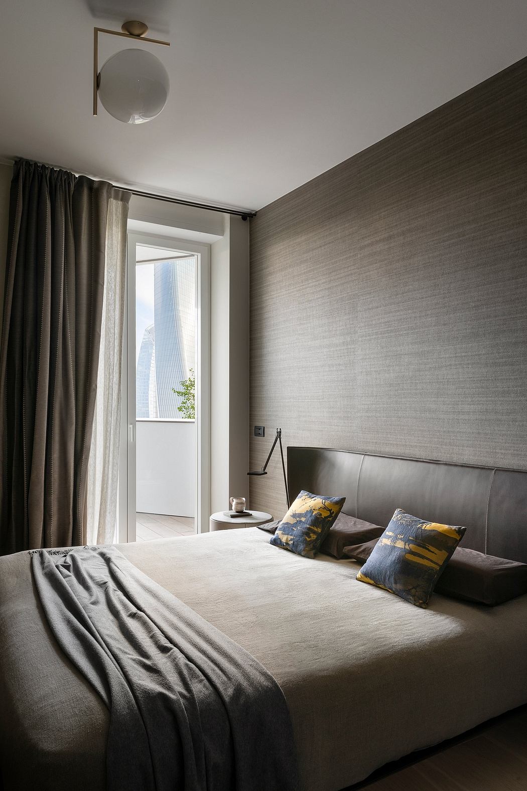 Cozy bedroom with textured gray walls, plush bedding, and modern lighting fixture.