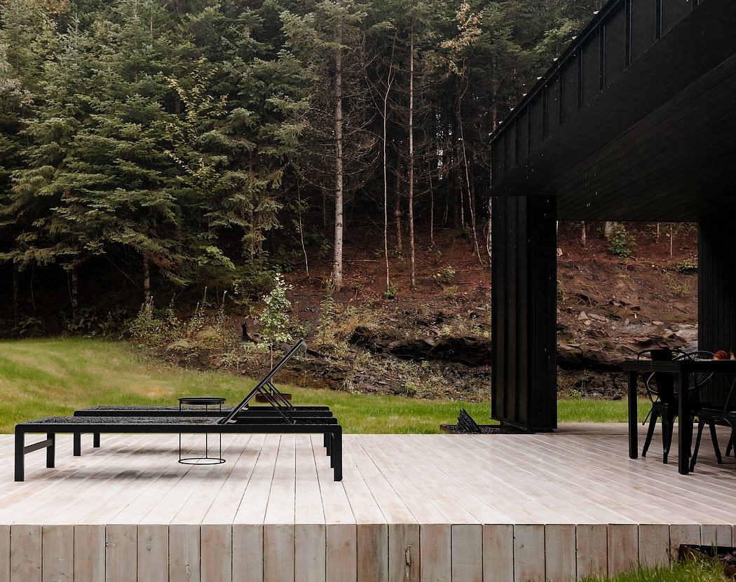 A modern, minimalist deck design overlooking a lush forest, featuring sleek black furniture and wooden accents.