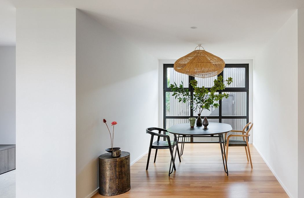 Minimalist dining area with modern furniture, pendant light, and lush plant decor.