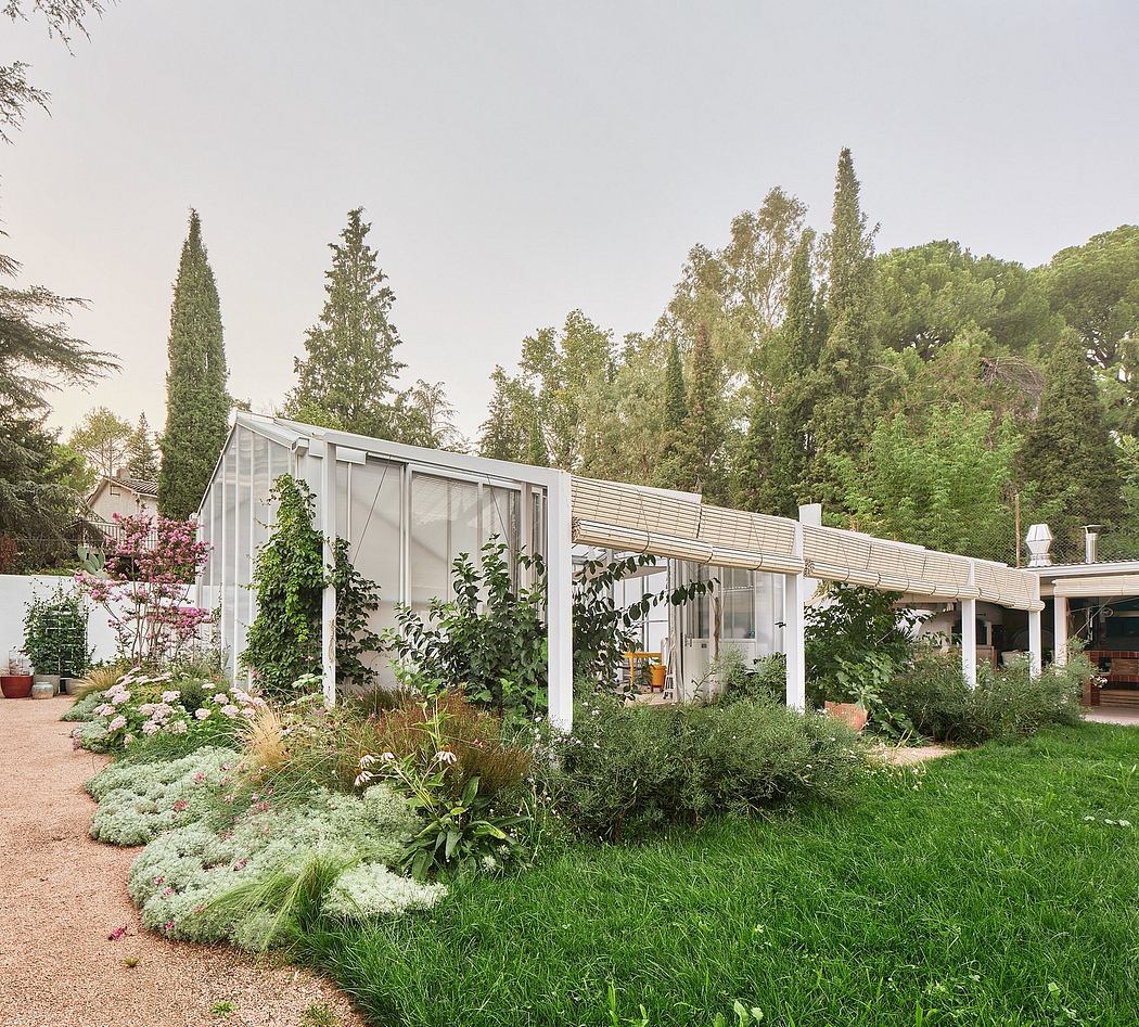 A modernist glass and wood structure surrounded by a lush, well-tended garden.