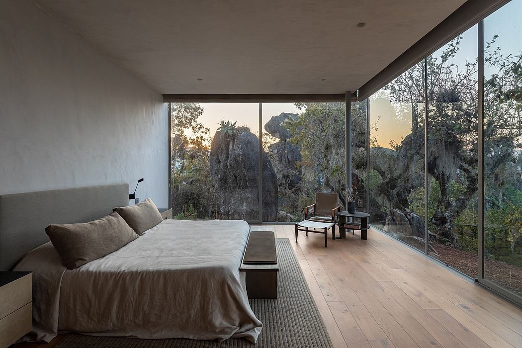 Expansive modern bedroom with floor-to-ceiling windows overlooking rugged landscape.