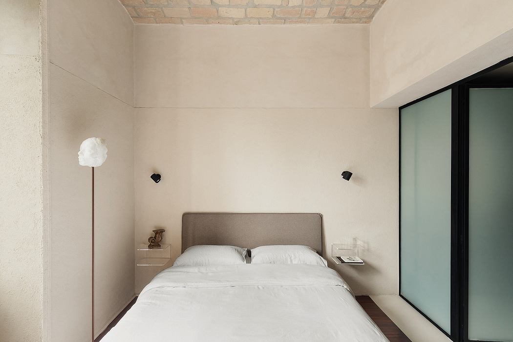 Minimalist bedroom with neutral tones, exposed brick, and large sliding glass door.