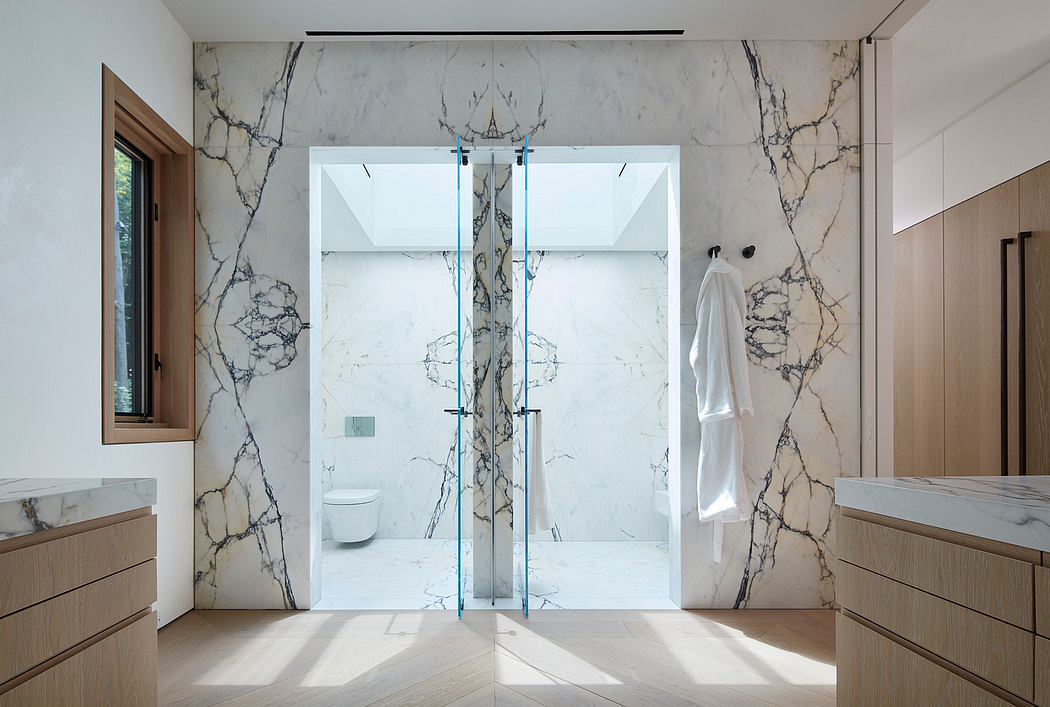 A modern, minimalist bathroom with white marble walls, glass shower, and wooden vanity.