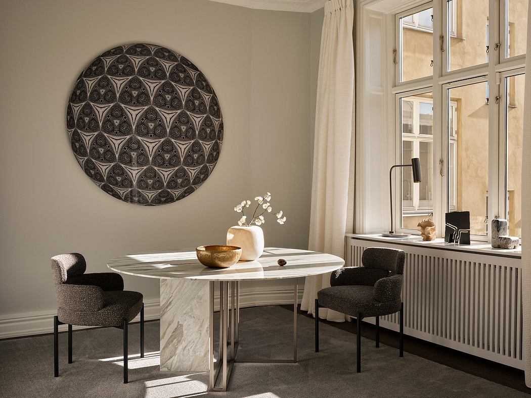 Elegant dining area with round marble table, plush chairs, and a decorative wall art.