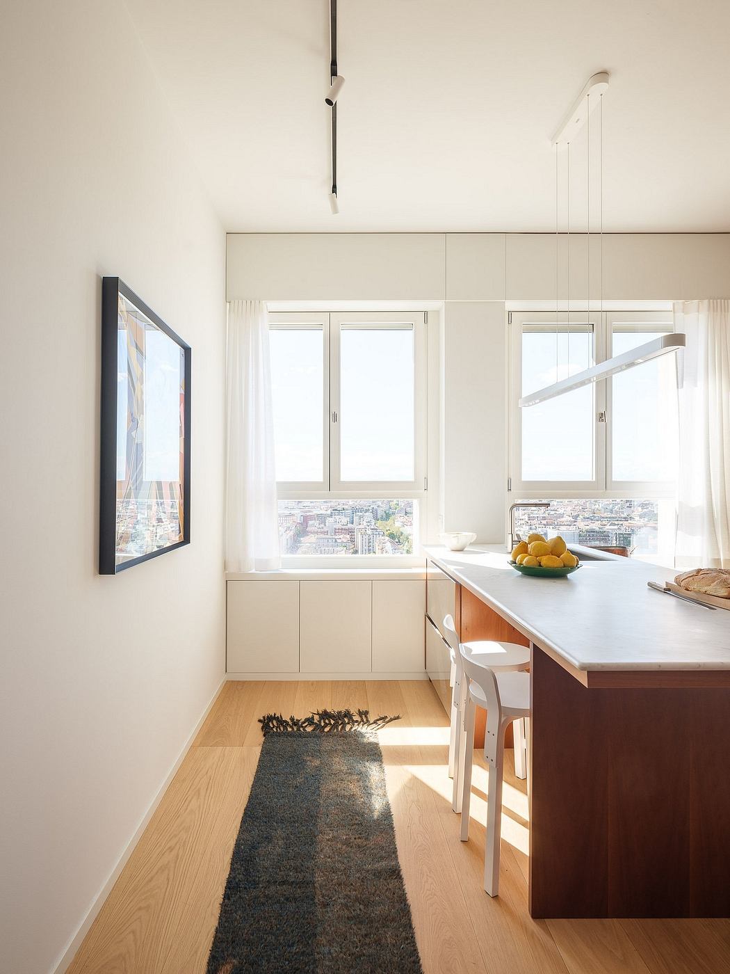 Bright, open kitchen with minimalist cabinetry, large windows, and modern pendant lighting.