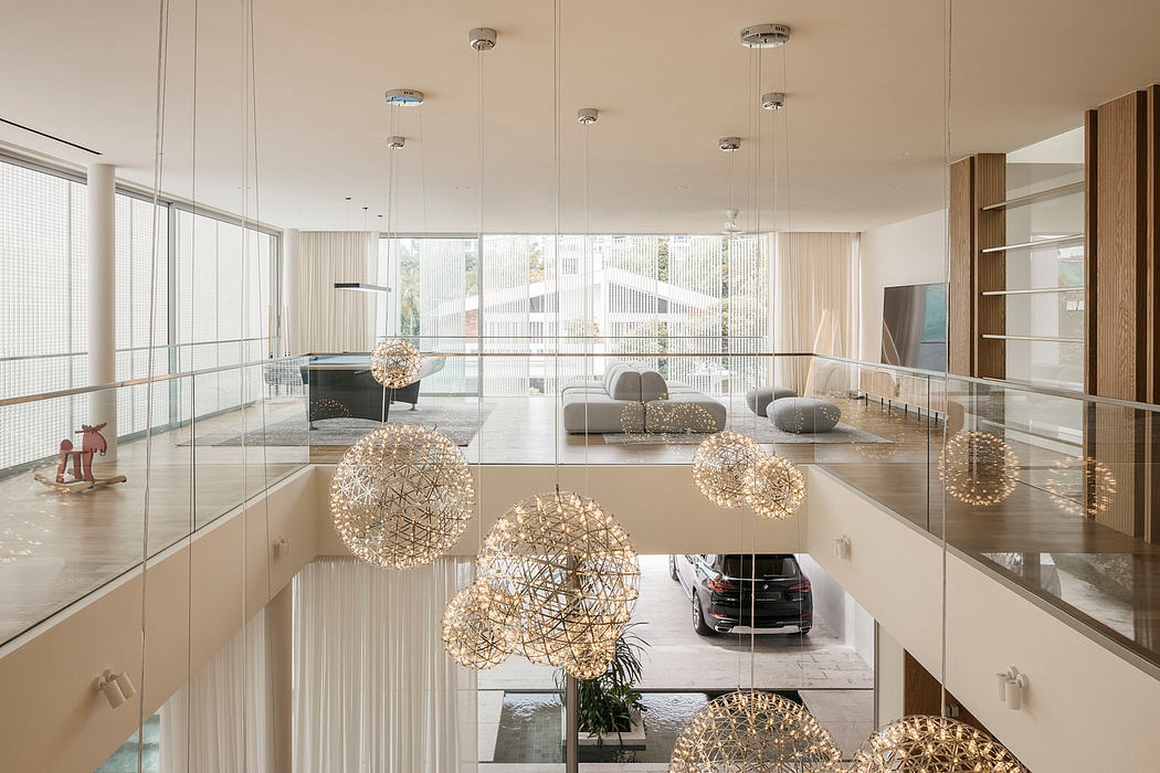 An expansive, modern lobby with geometric light fixtures and glass walls showcasing a car.
