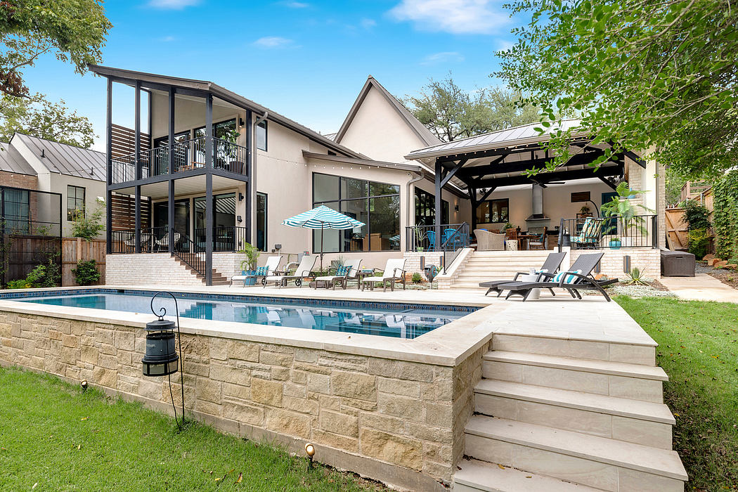 Modern two-story home with stone exterior, covered patio, and in-ground pool.