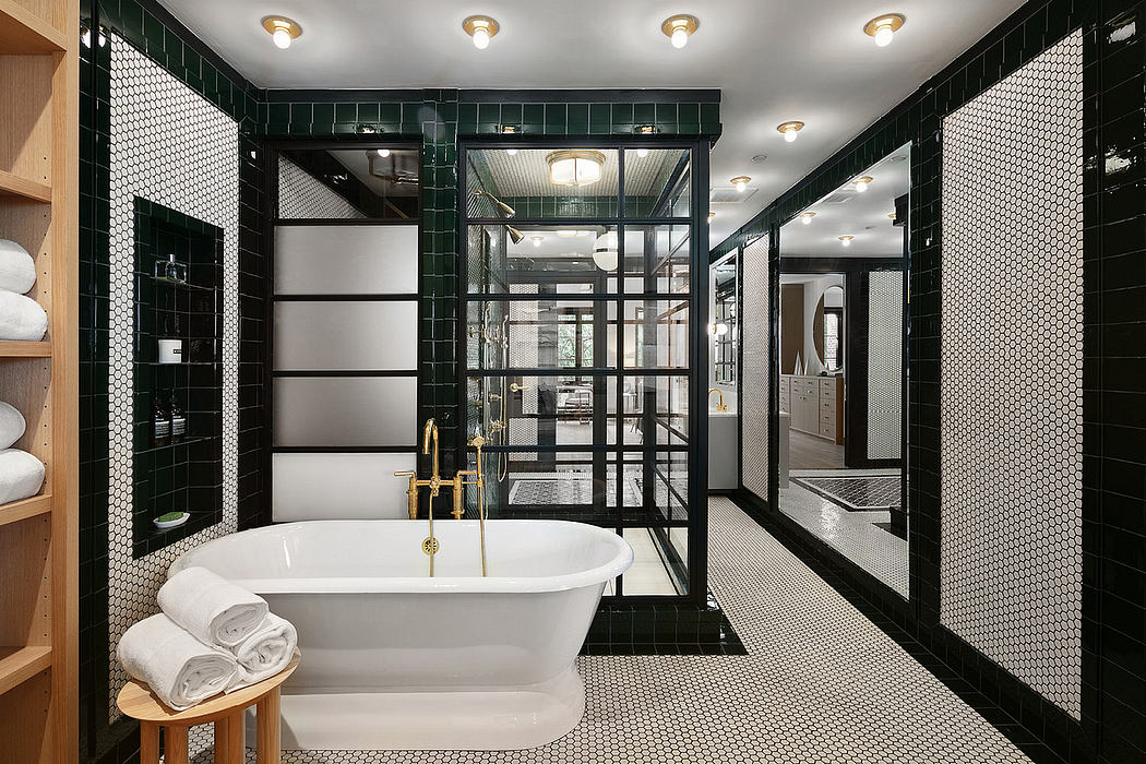 Elegant modern bathroom with freestanding tub, black tile walls, and gold fixtures.