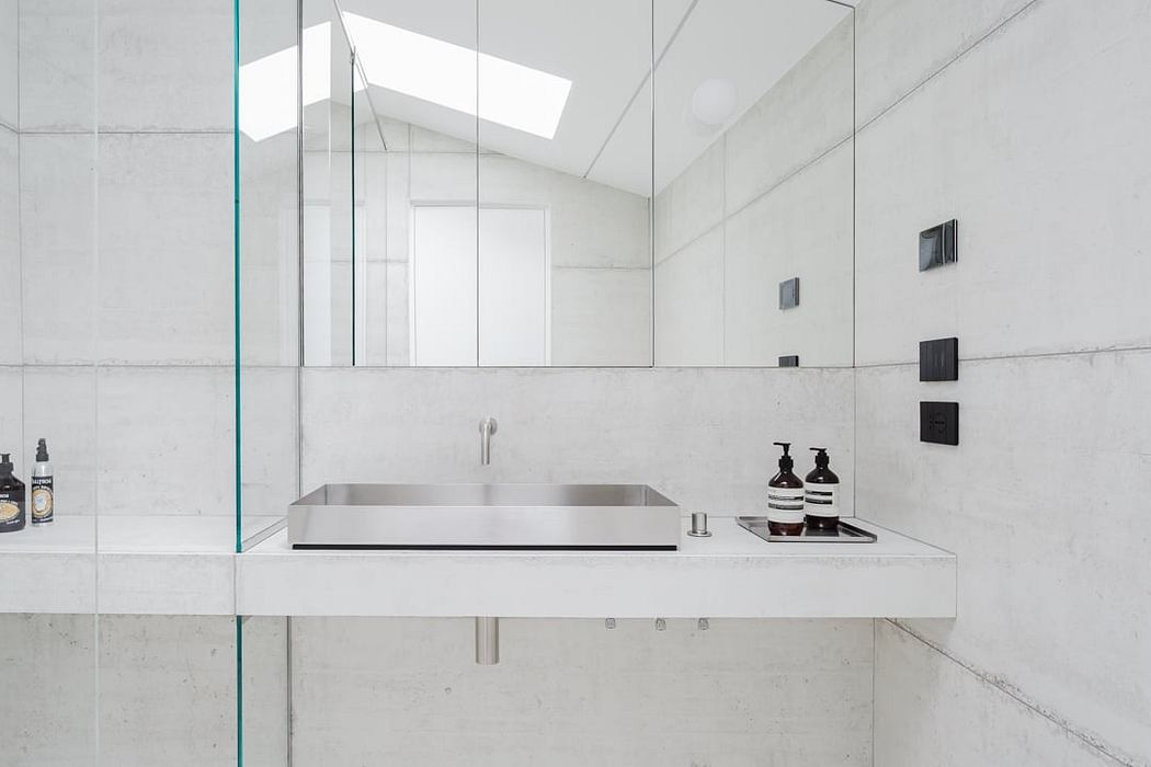 Modern, minimalist bathroom with sleek stainless steel sink, glass walls, and clean lines.