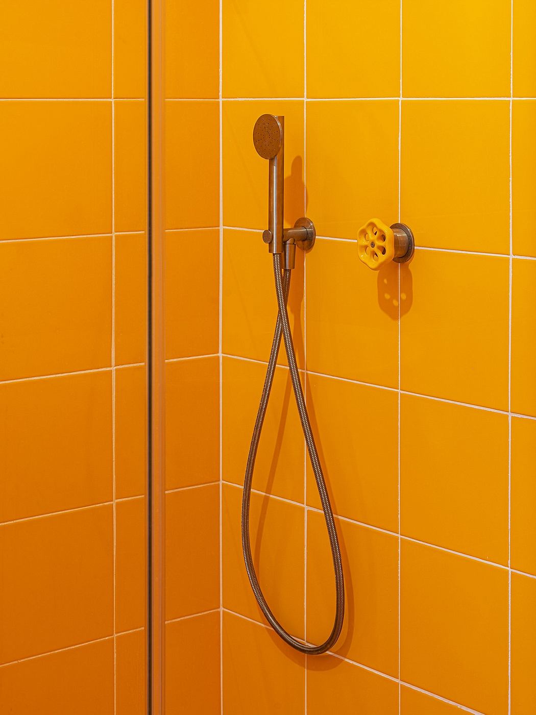 A modern, vibrant shower with bold yellow tiles and a sleek metal showerhead.