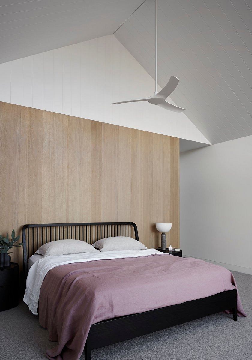 Minimalist bedroom with wooden paneling, white ceiling, and modern ceiling fan.