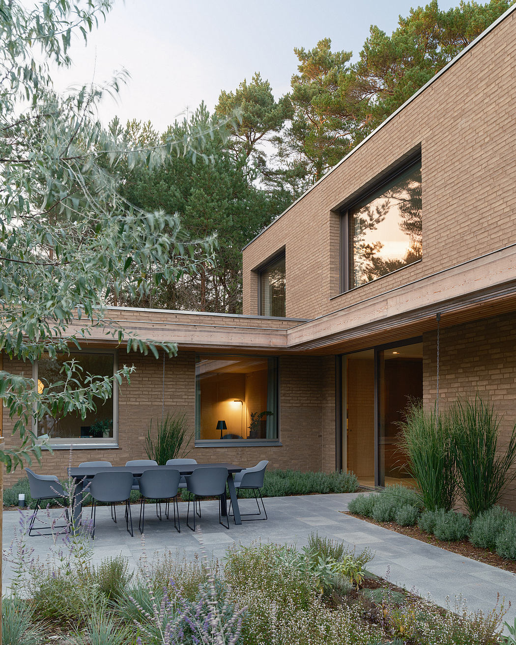 Modern brick home with outdoor dining area, garden landscaping, and large windows.