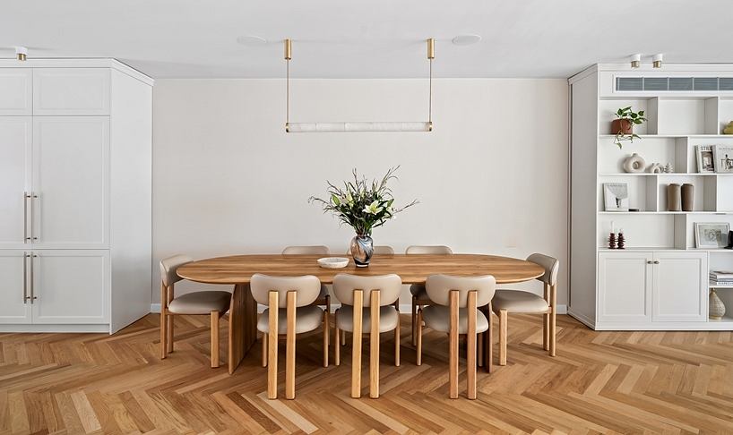 Minimalist dining room with wooden table, chairs, and built-in shelves on the walls.