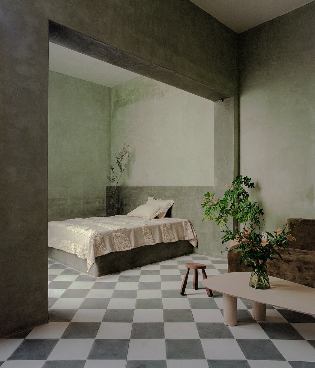 Minimalist bedroom with concrete walls, checkerboard tile floor, and natural furnishings.