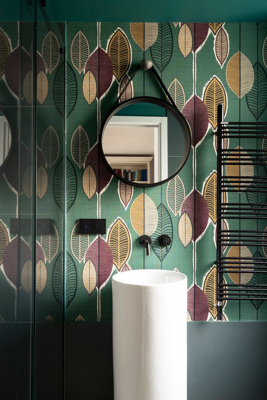 A modern bathroom with a vibrant, leafy wallpaper and a sleek, white basin.