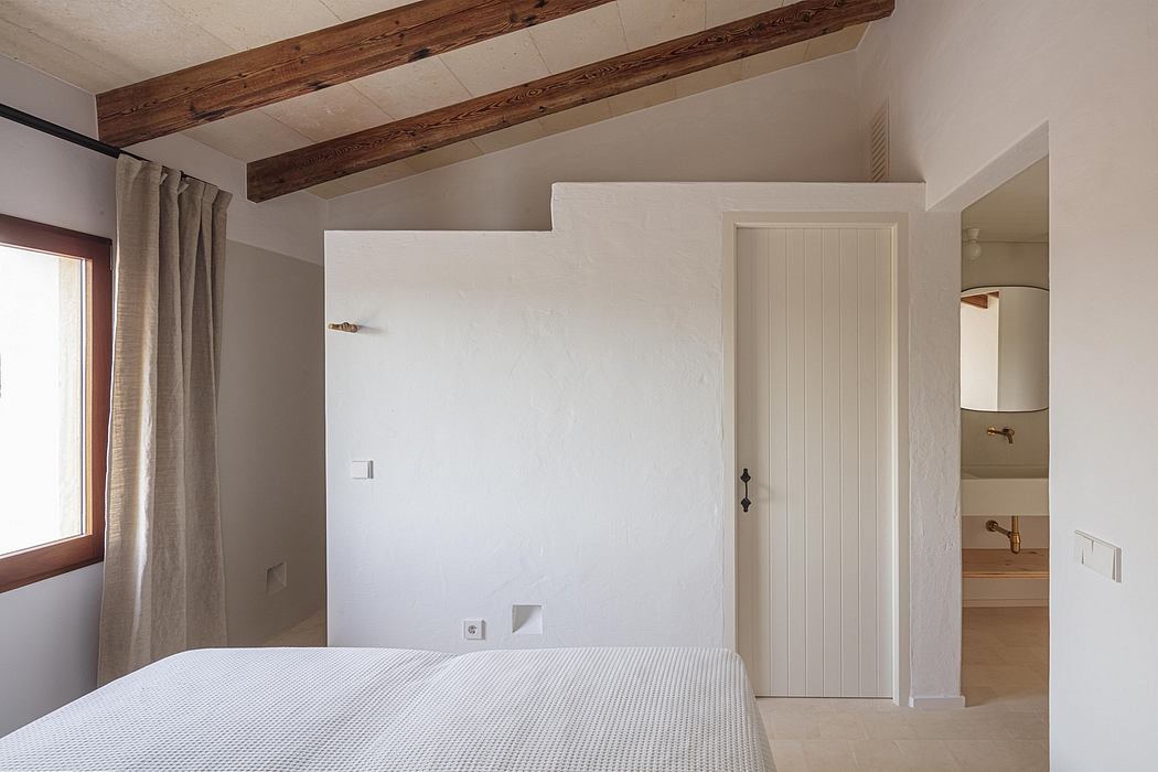 Minimalist bedroom with wooden ceiling beams, neutral tones, and a simple white door.