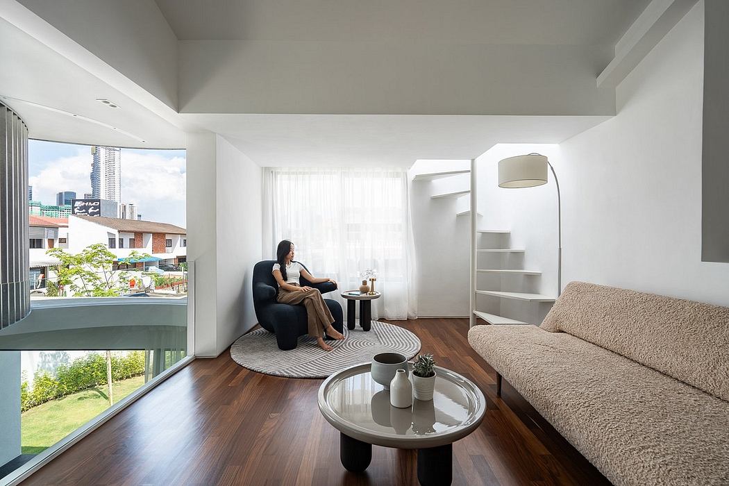 Bright, minimalist living room with large windows, sofa, coffee table, and shelving unit.