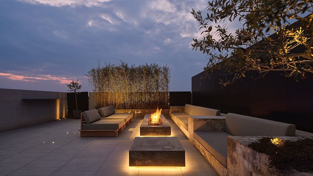 Outdoor patio with cozy seating, firepit, and lighting under an evening sky.