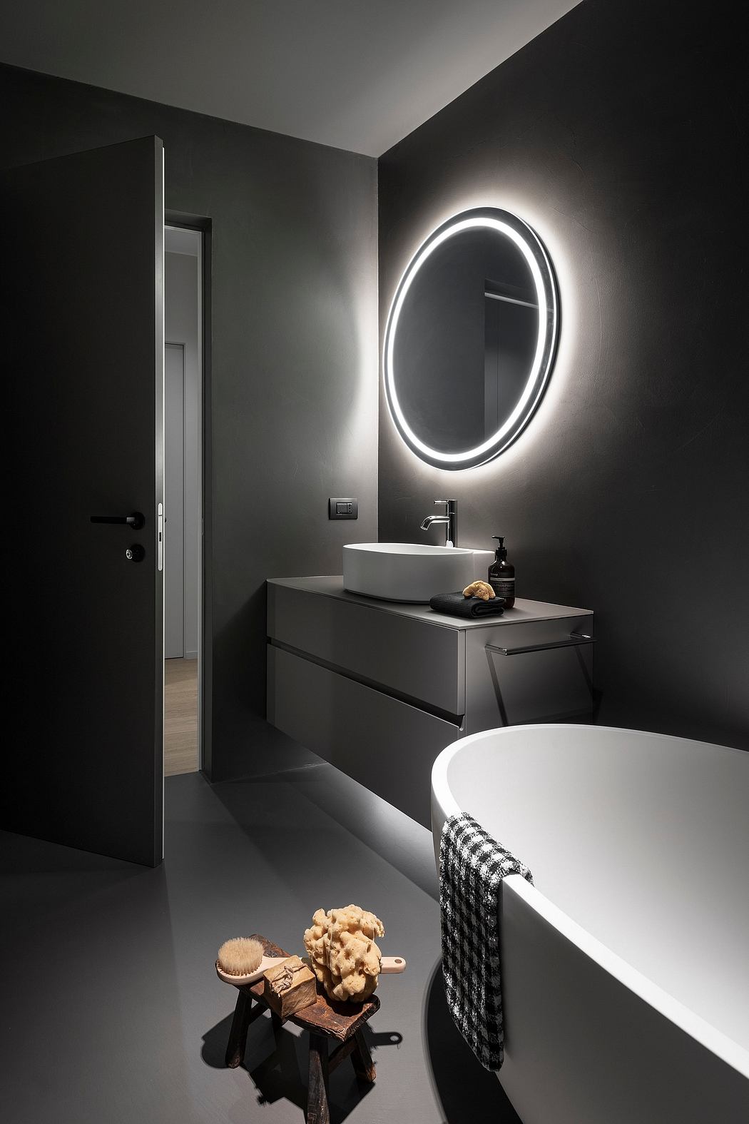 Sleek, modern bathroom with backlit oval mirror, minimalist sink vanity, and patterned towel.
