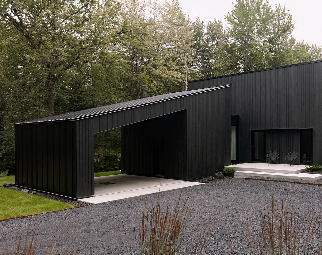 A modern, black-clad structure with clean lines and a cantilevered roof, nestled among lush greenery.