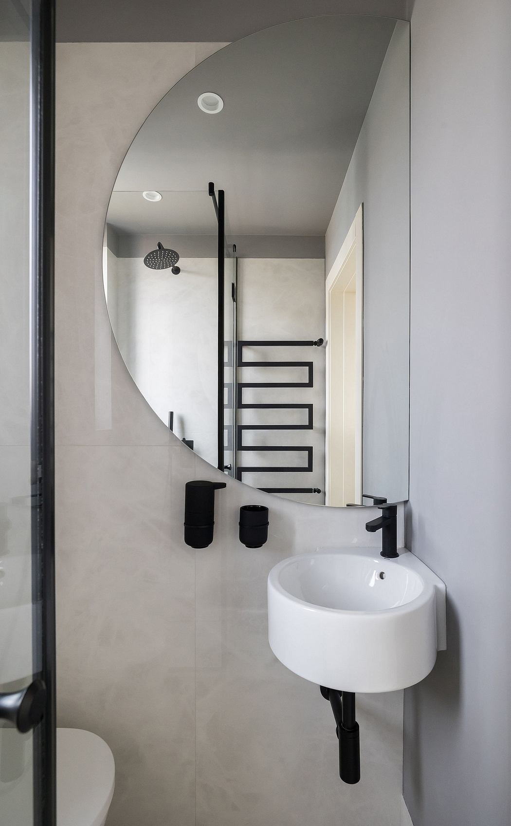 Sleek, modern bathroom with curved mirror, minimalist black hardware, and recessed lighting.