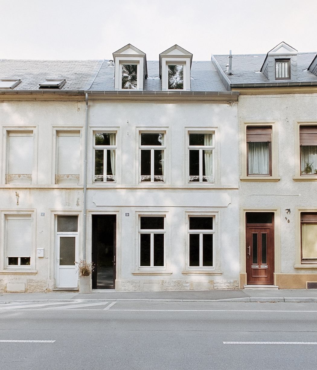 Charming multi-story building with ornate windows, doors, and a tiled roof, set against a gray sky.