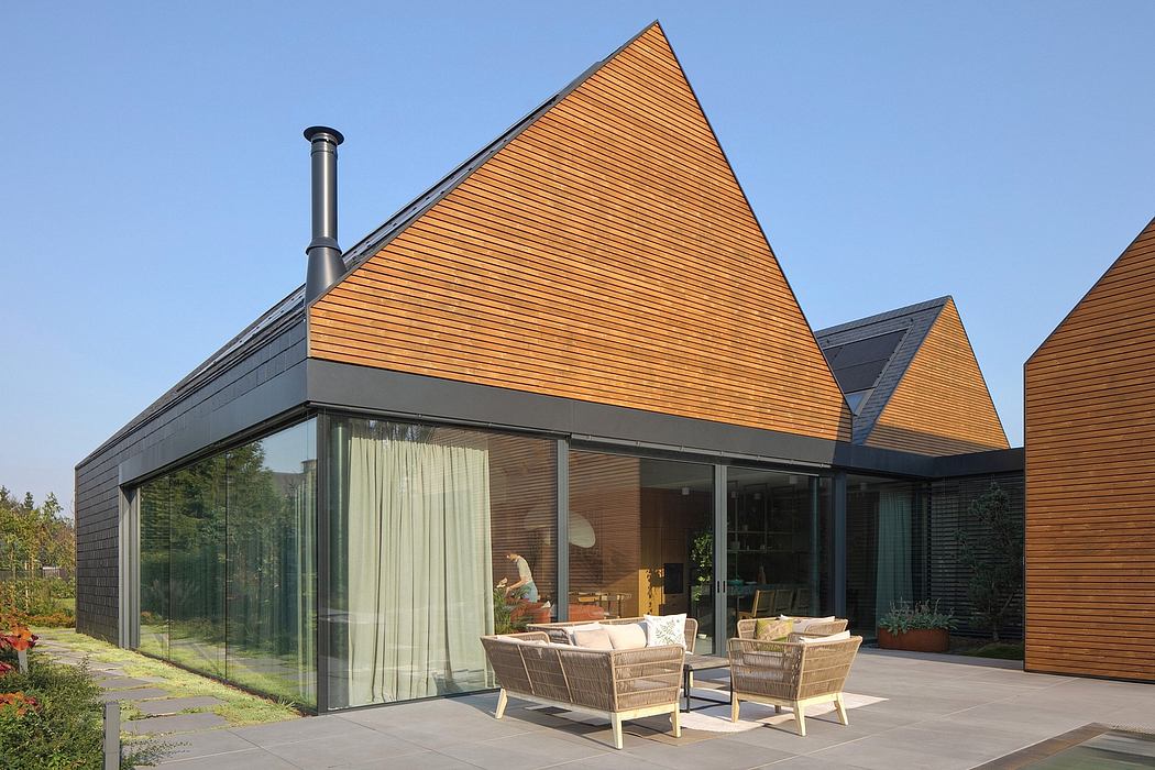 Contemporary glass and wood exterior with angled roof and outdoor seating area.