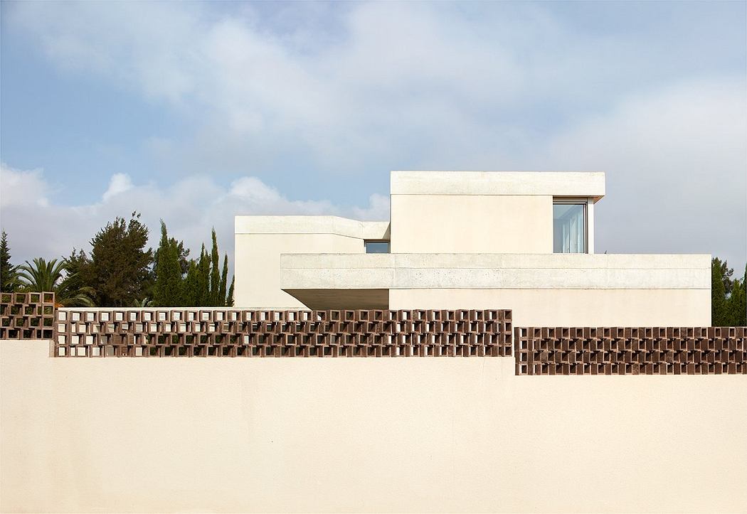 A modern, minimalist building with a unique, geometric brick facade against a blue sky.
