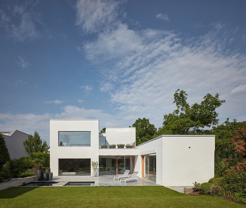 Modern minimalist home with clean white facades, glass walls, and lush landscaping.