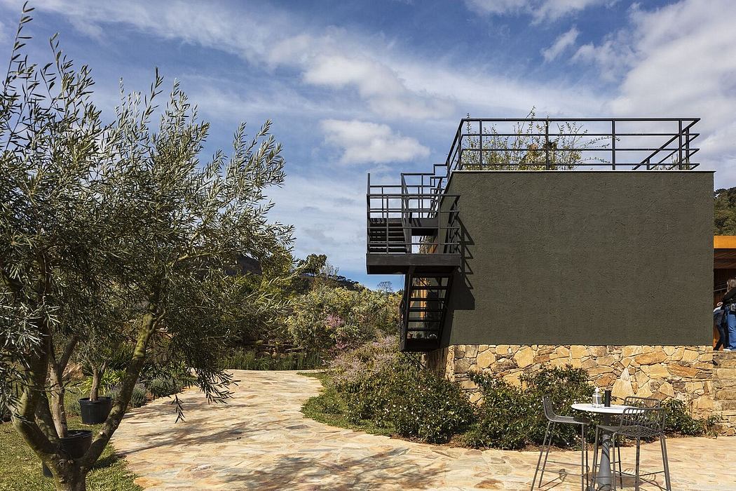 Modern stone and metal building with outdoor seating area and lush landscaping.