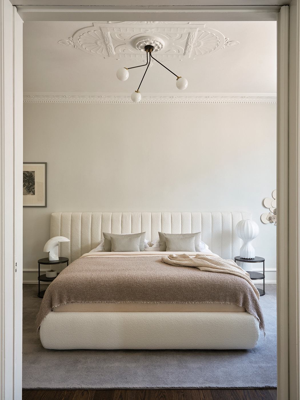 Elegant bedroom with plush upholstered headboard and ornate ceiling molding.