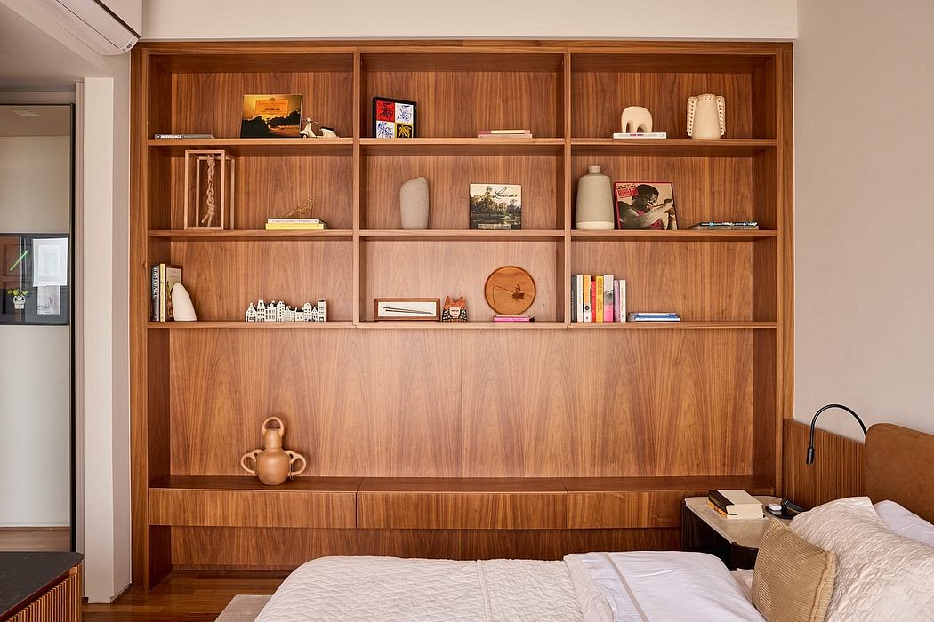 A modern, wooden shelving unit with decorative objects and personal items displayed.