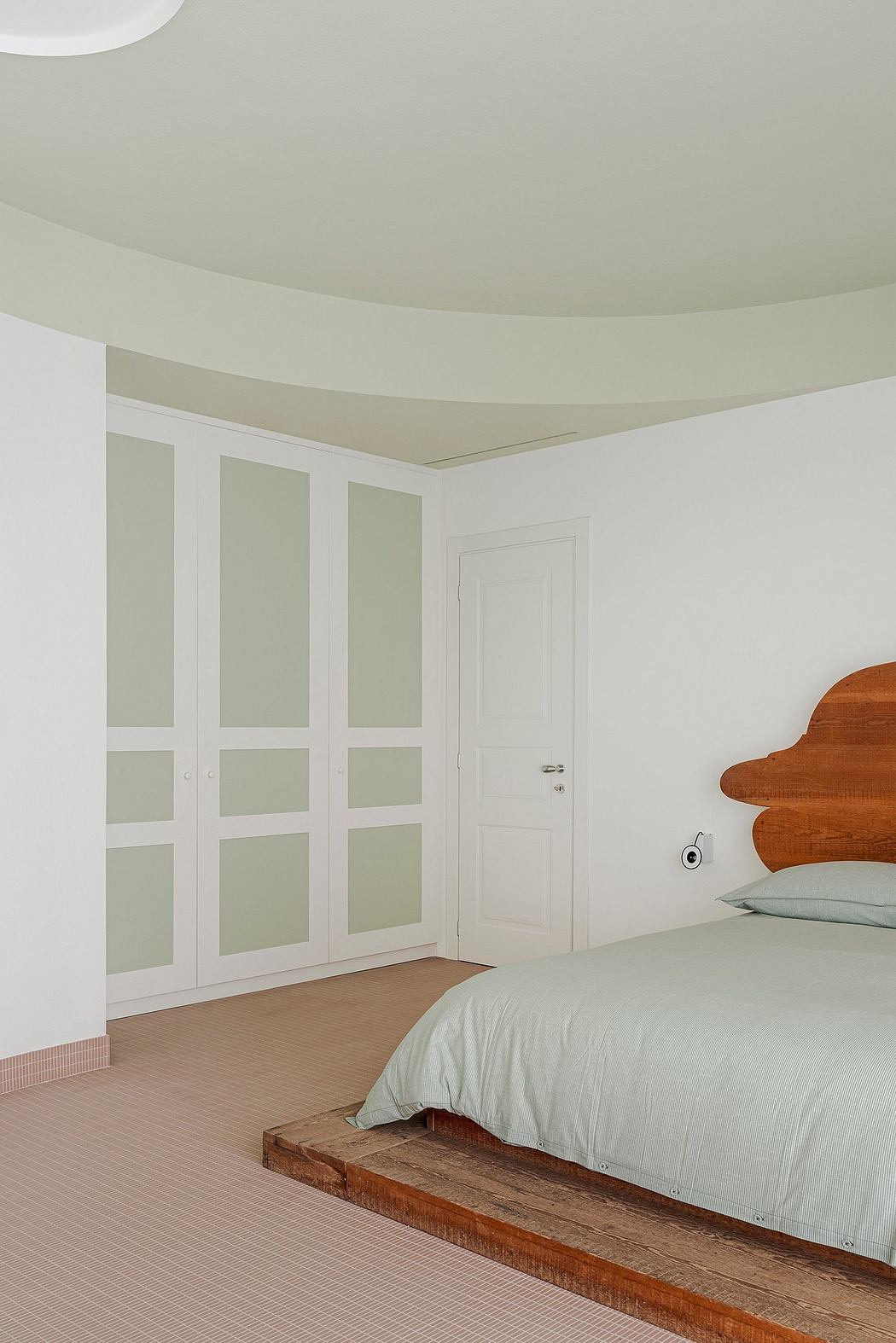 Minimalist bedroom with curved ceiling, glass-paneled wardrobe, and wooden platform bed.