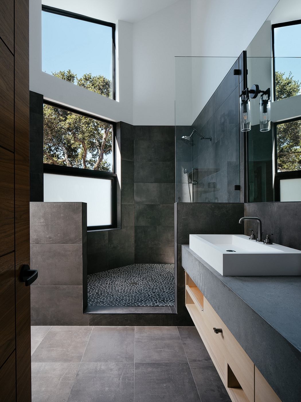 Sleek modern bathroom with large windows, dark tiles, and a vessel sink vanity.