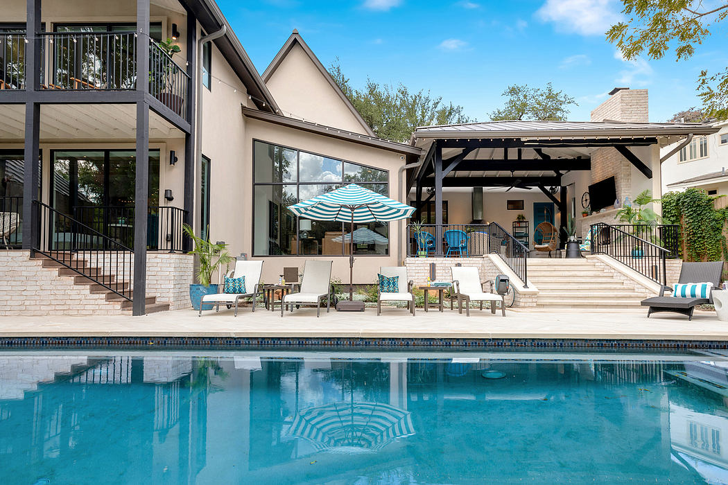Elegant home exterior with a covered patio, in-ground pool, and modern furnishings.
