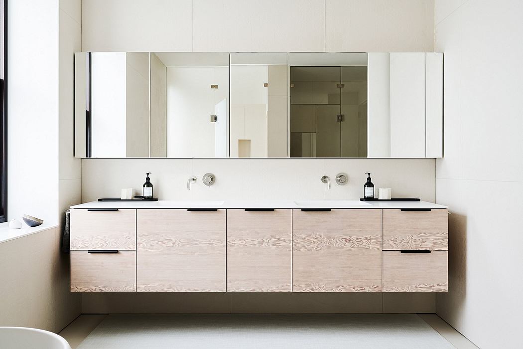 Minimalist bathroom with floating white oak vanity, large mirror, and black hardware.