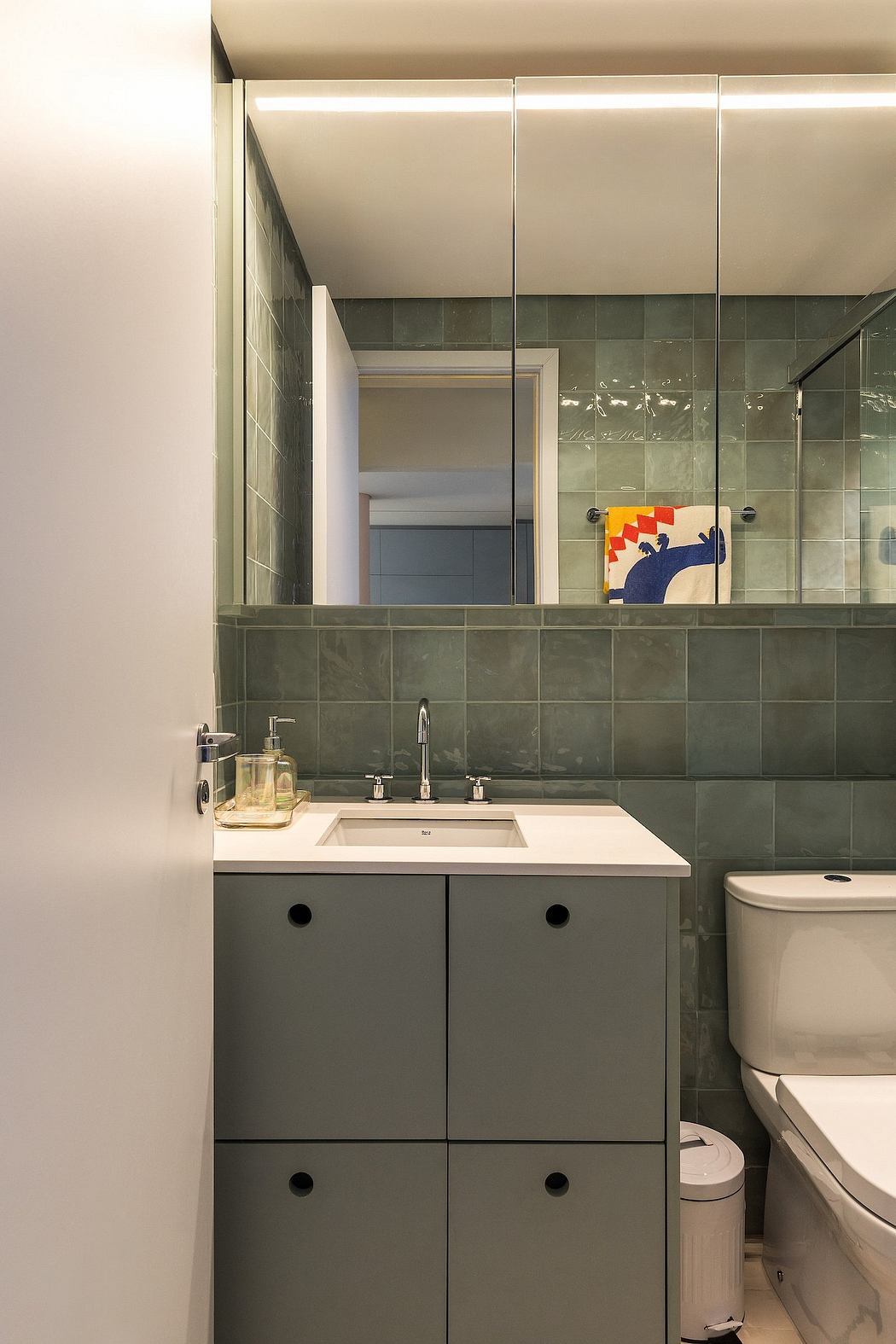 Modern bathroom with gray tiled walls, white vanity, and recessed lighting.