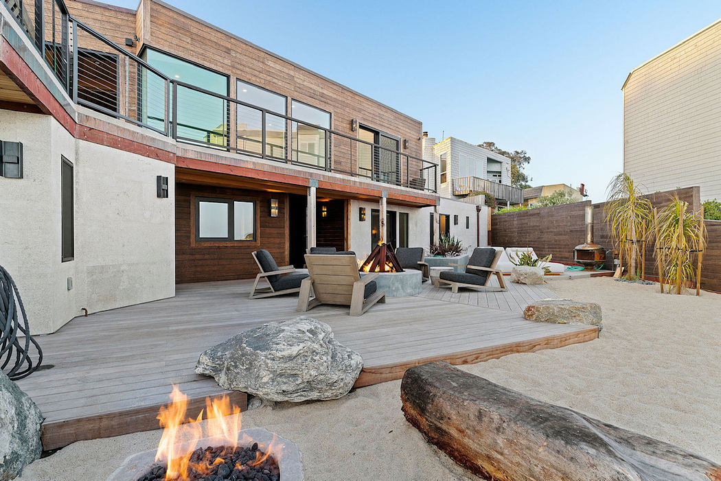 A modern, multi-level wooden structure with a large outdoor deck and a fire pit.