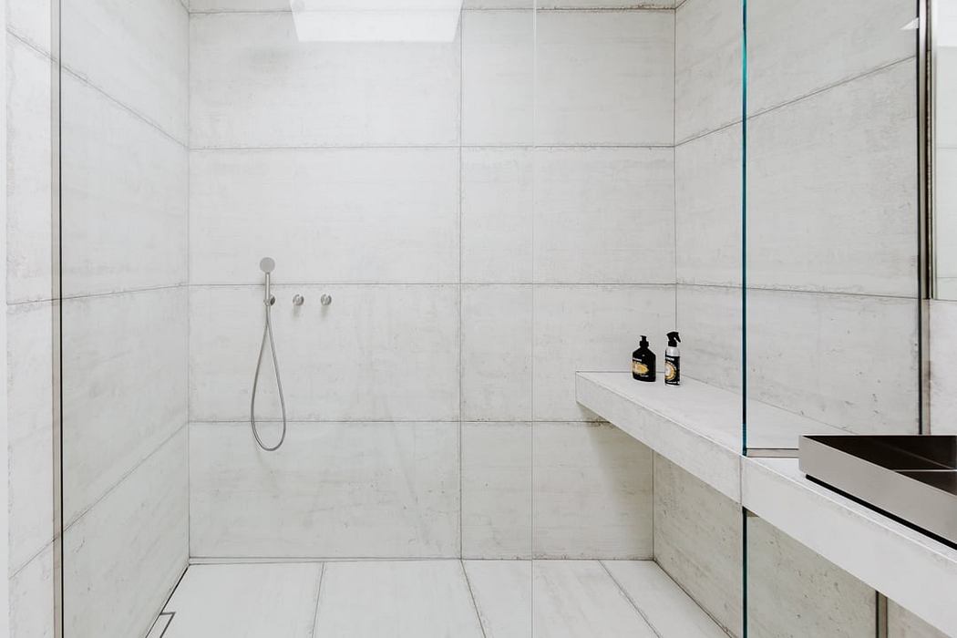 Minimalist, modern bathroom with sleek tiled walls and a built-in vanity.