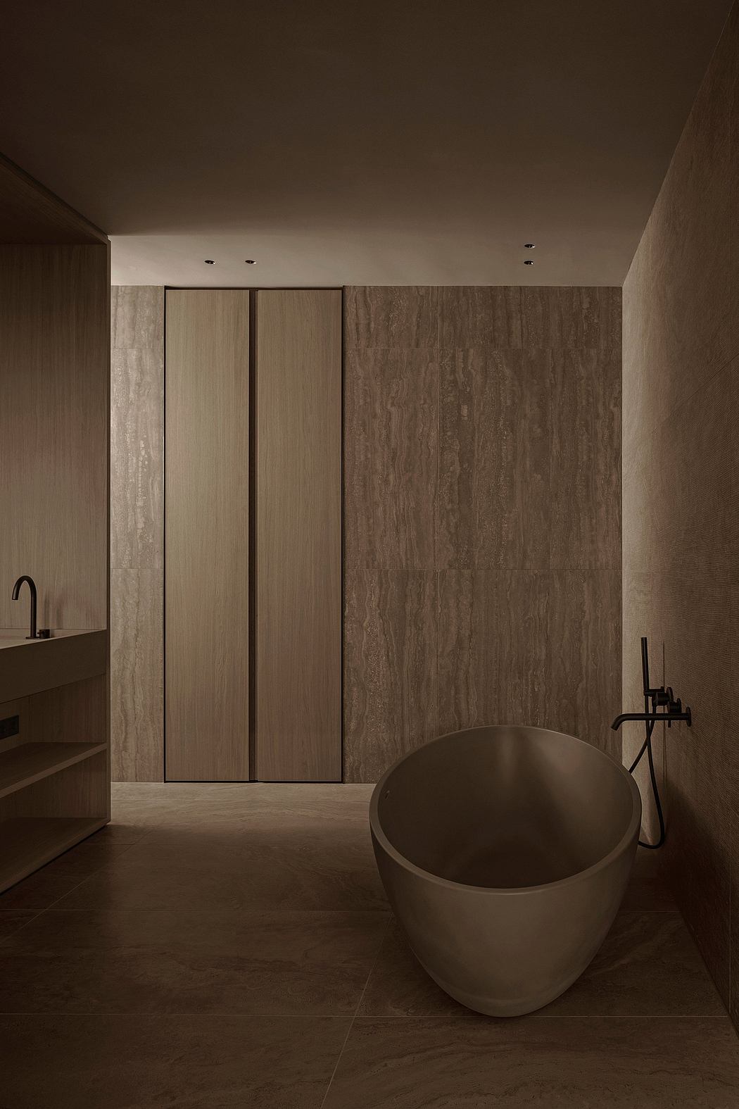 A minimalist bathroom with a round freestanding tub, sleek cabinets, and textured stone walls.