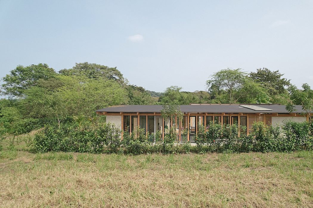 Rustic wooden building surrounded by lush greenery in natural landscape.