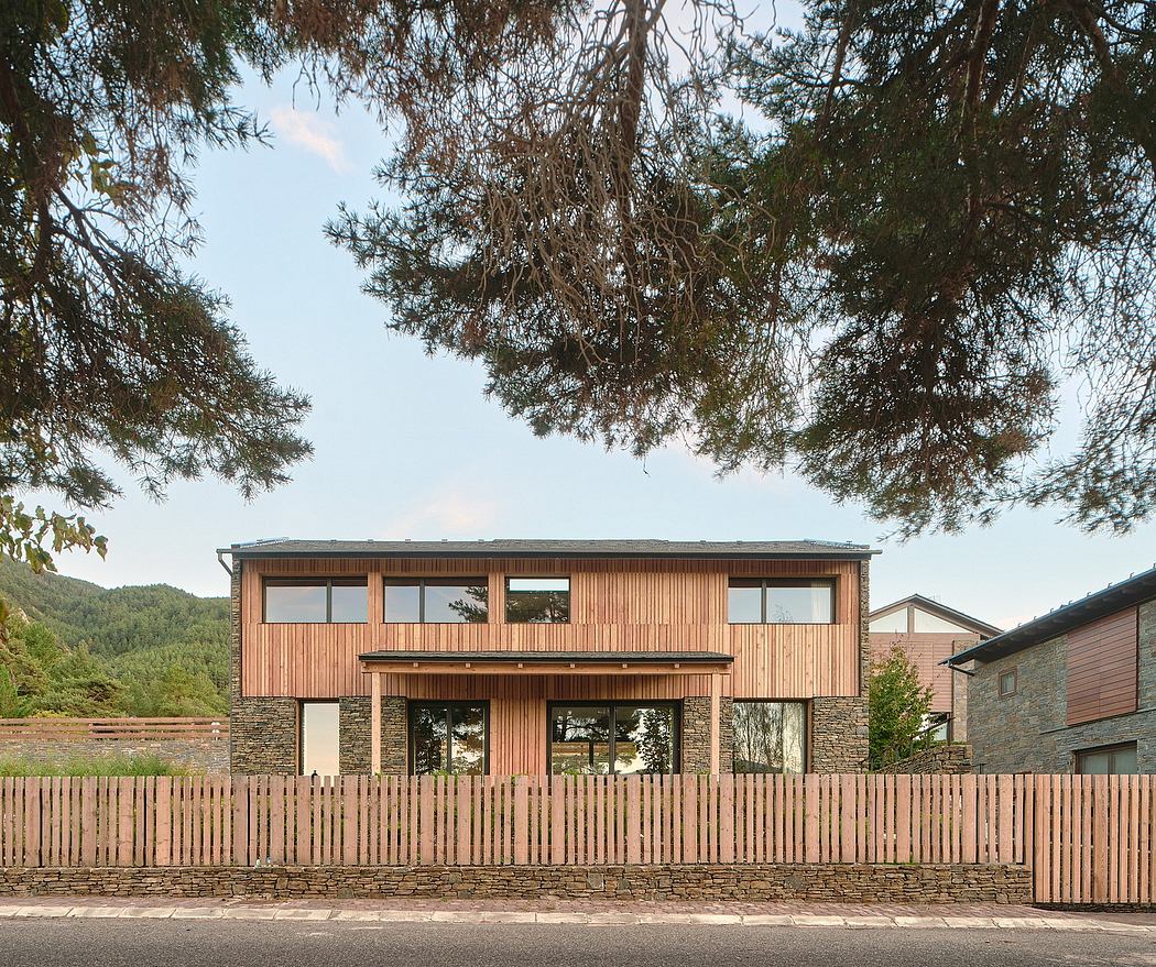 Wooden exterior with large windows and stone facade, surrounded by fencing.