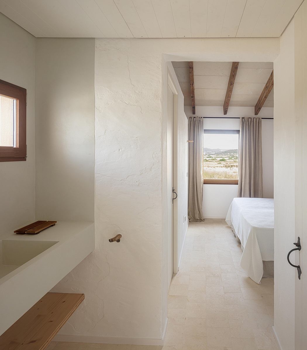 Spacious bedroom with rustic wooden beams, white walls, and large window offering scenic view.