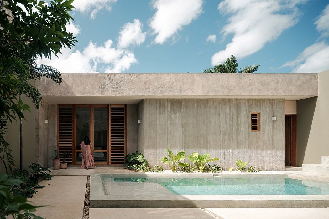 A modern concrete and wood home with a tranquil pool surrounded by lush vegetation.
