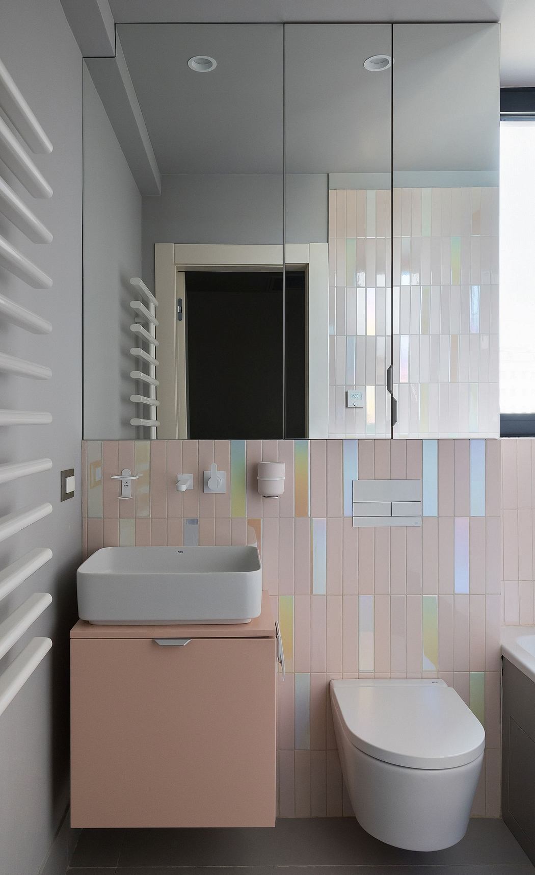 A modern bathroom with a sleek vanity, colorful tiled walls, and recessed lighting.