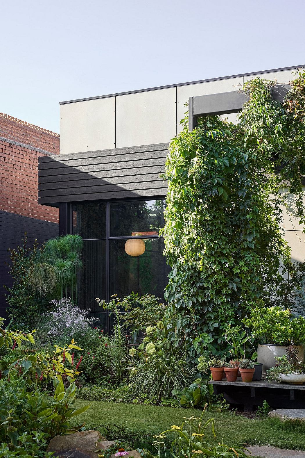 A modern, minimalist building with a lush, overgrown garden surrounding it, creating a serene atmosphere.
