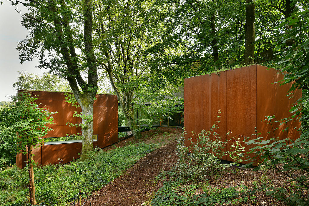 A picturesque forest path lined with striking rust-colored metal sculptures.
